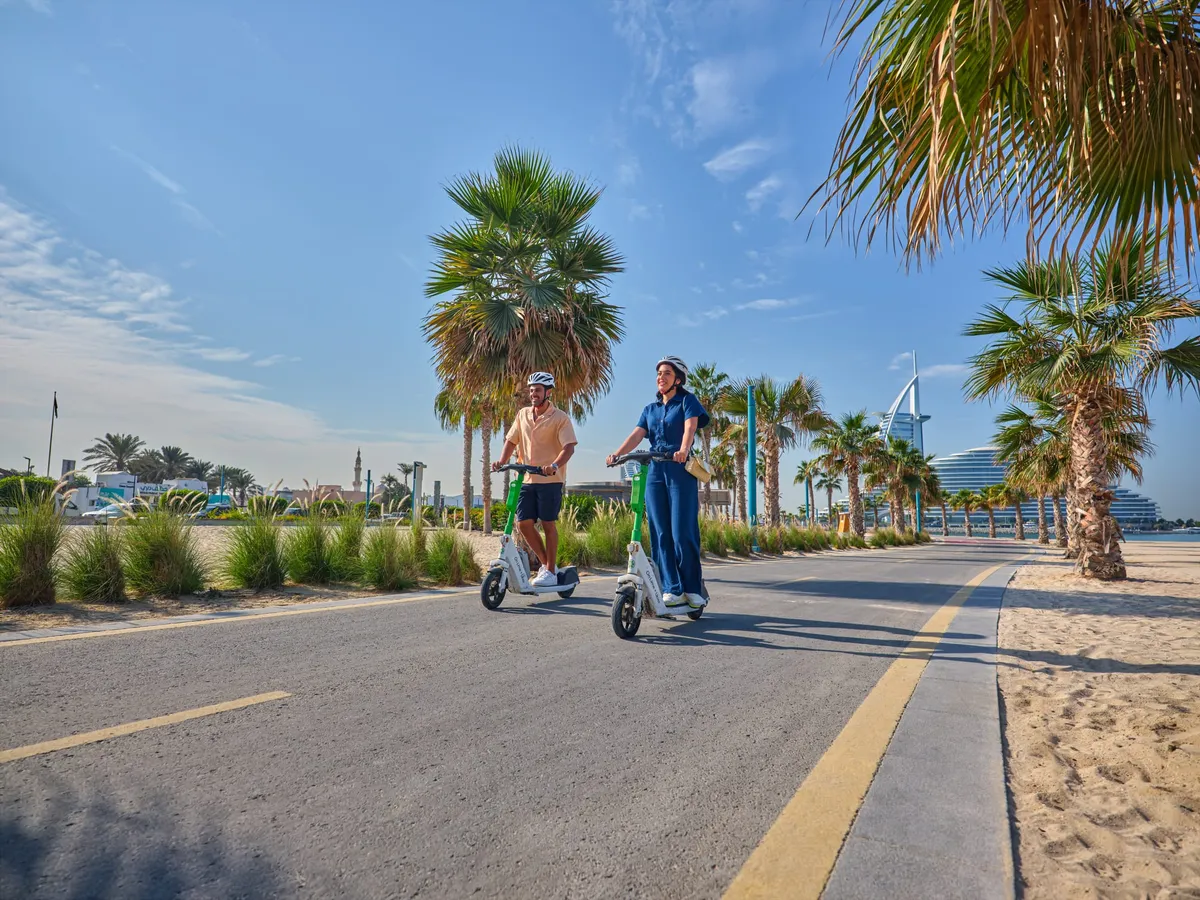Sunbathers relaxing on Kite Beach in Dubai with the city skyline in the background.