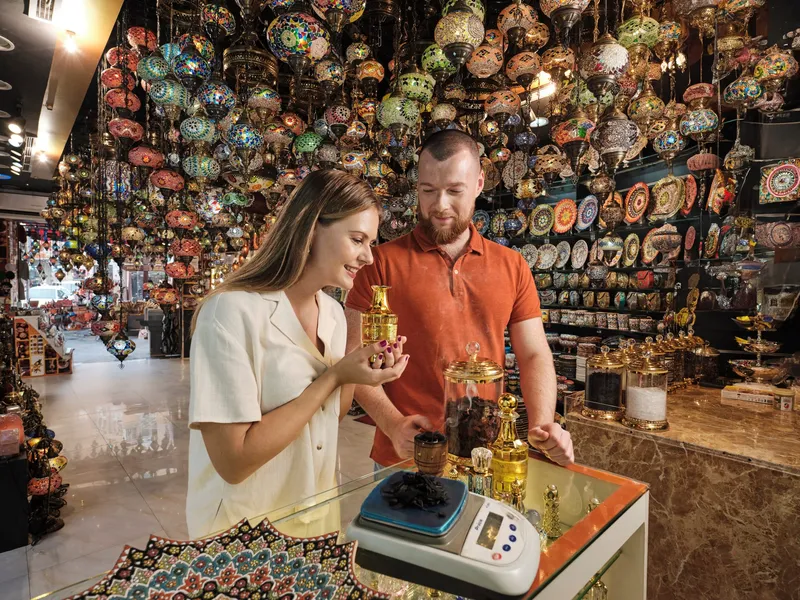 Shoppers browsing the Dubai Perfume Souk in Deira, with rows of fragrance bottles on display.