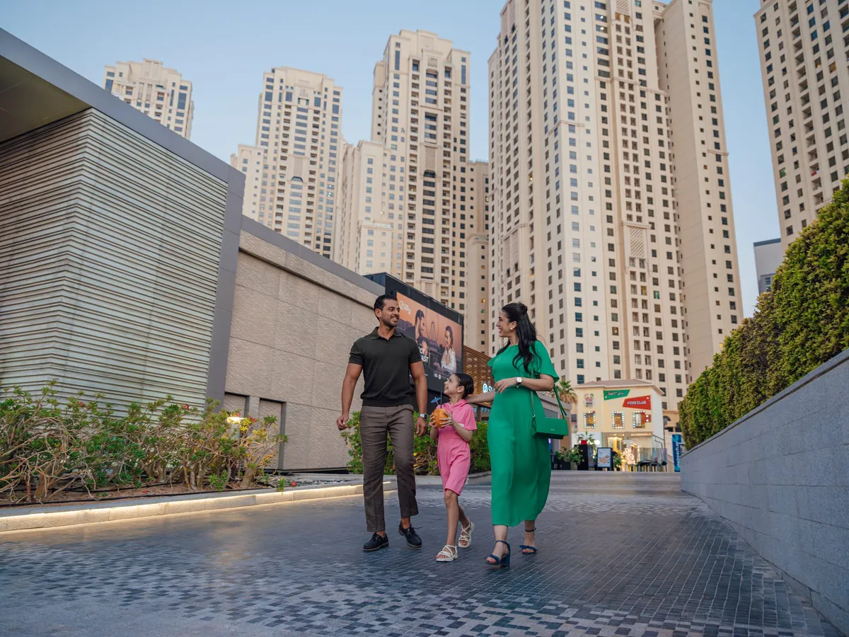 JBR beachfront promenade with beach-goers and the Dubai skyline behind